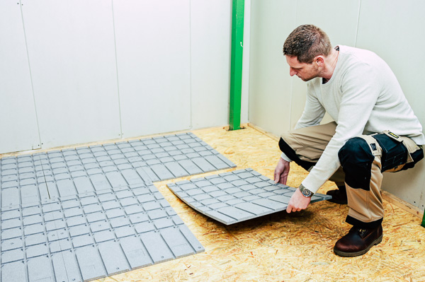 Man installeert vloerverwarming op houten vloer